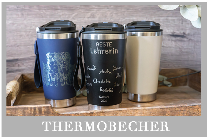 Schwarzer Edelstahl-Thermobecher mit personalisierter Lasergravur auf Holzuntergrund, umgeben von Eukalyptus