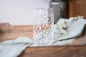 Preview: Can Longdrinkglas mit weißen Herzen, 470 ml, dekorativ auf einem Holztablett mit Stofftuch arrangiert