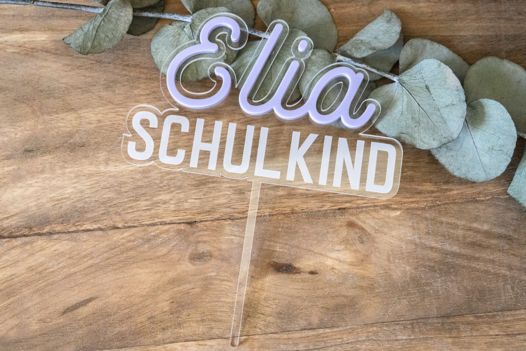 Cake Topper Schulkind mit Namen Elia in Flieder auf Holzuntergrund mit Eukalyptuszweig, name Flieder