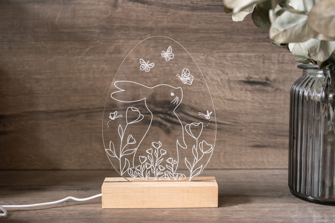 LED Osterlampe aus Acrylglas mit Hasenmotiv im Osterei, Blumen und Schmetterlingen auf Holzsockel, warmweiß beleuchtet