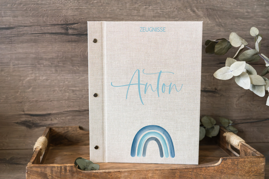 Personalisierte Zeugnismappe für Jungen in Leinenoptik mit Regenbogen-Motiv in Blautönen (Beispielname: Anton)